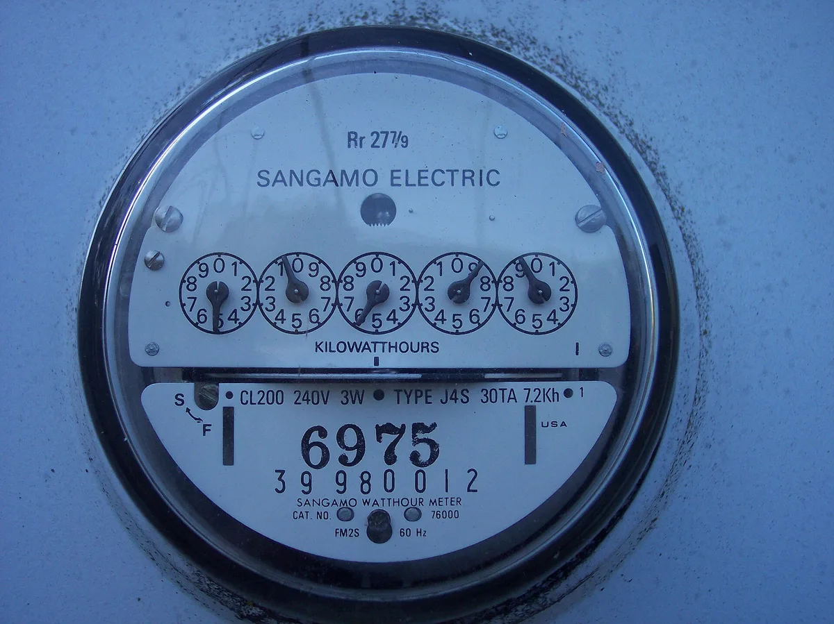 Close-up of an analogue kilowatt-hour electricity meter showing five register dials and a rating plate.